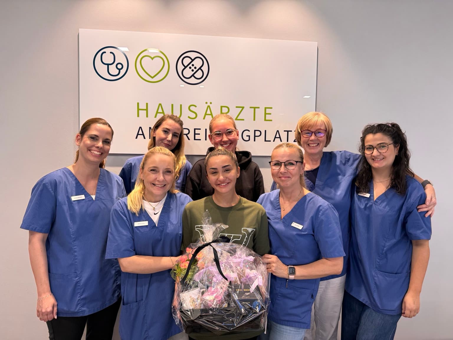 Foto des Praxisteams, Marwa Semmo in der Mitte, hält einen Geschenkkorb